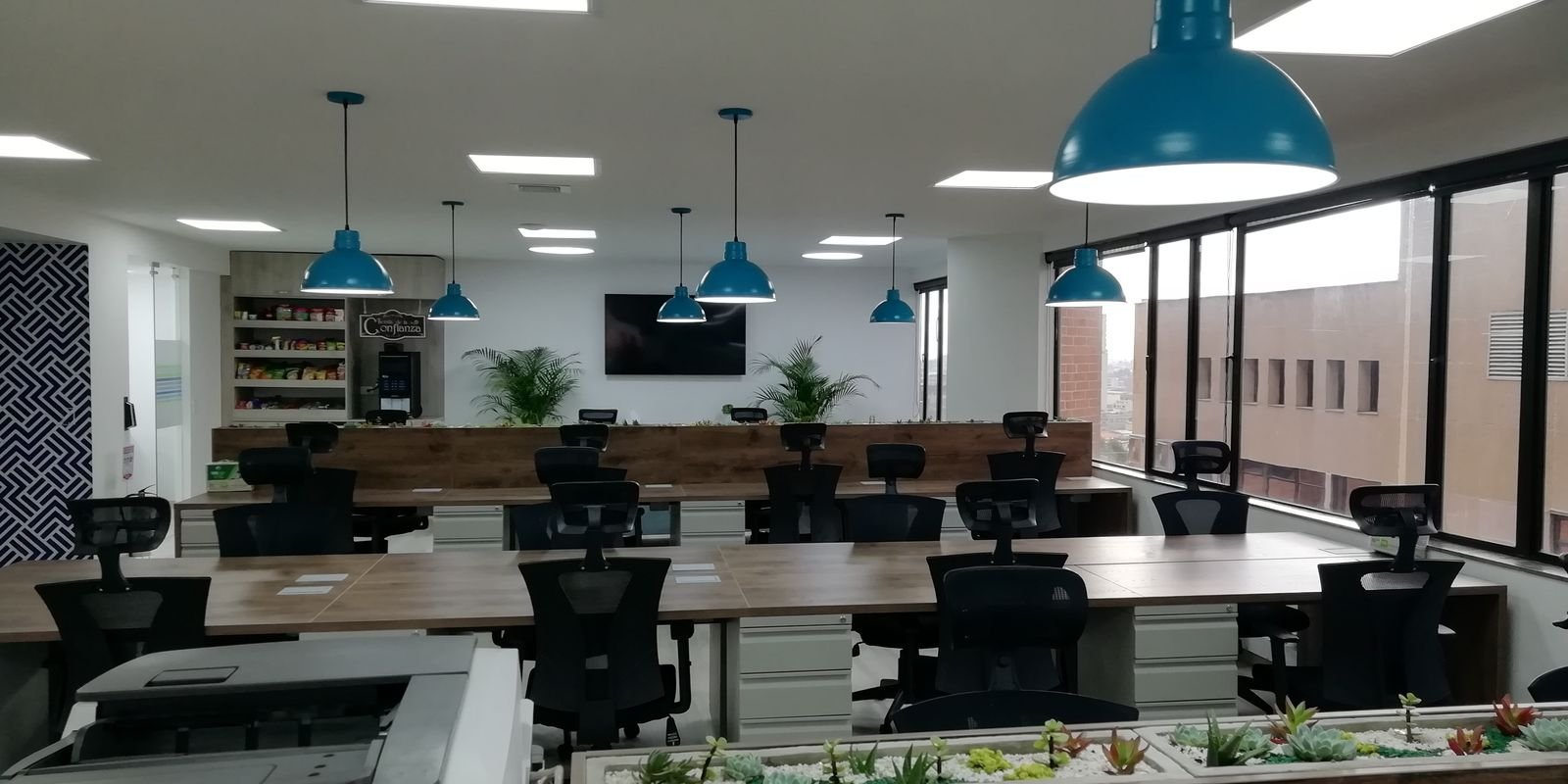 Oficina abierta remodelada con puestos de trabajo y lámparas colgantes
